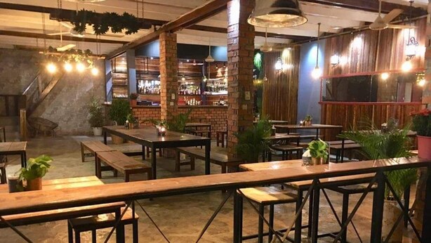 Un ristorante con pareti in mattoni, tavoli di legno e lampade a sospensione.