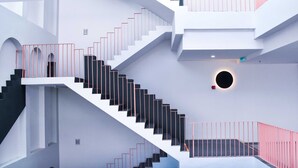 A modern interior with a central staircase, multiple levels, and a circular skylight. - Urban Inn Alor Setar (Alor Setar)