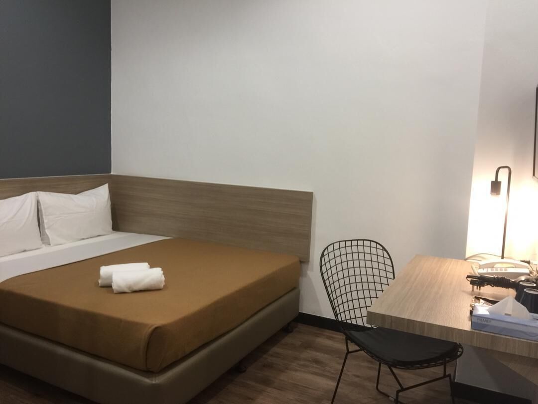 Ein Hotelzimmer mit einem Bett, einem Sessel und einem Schreibtisch mit Lampe.