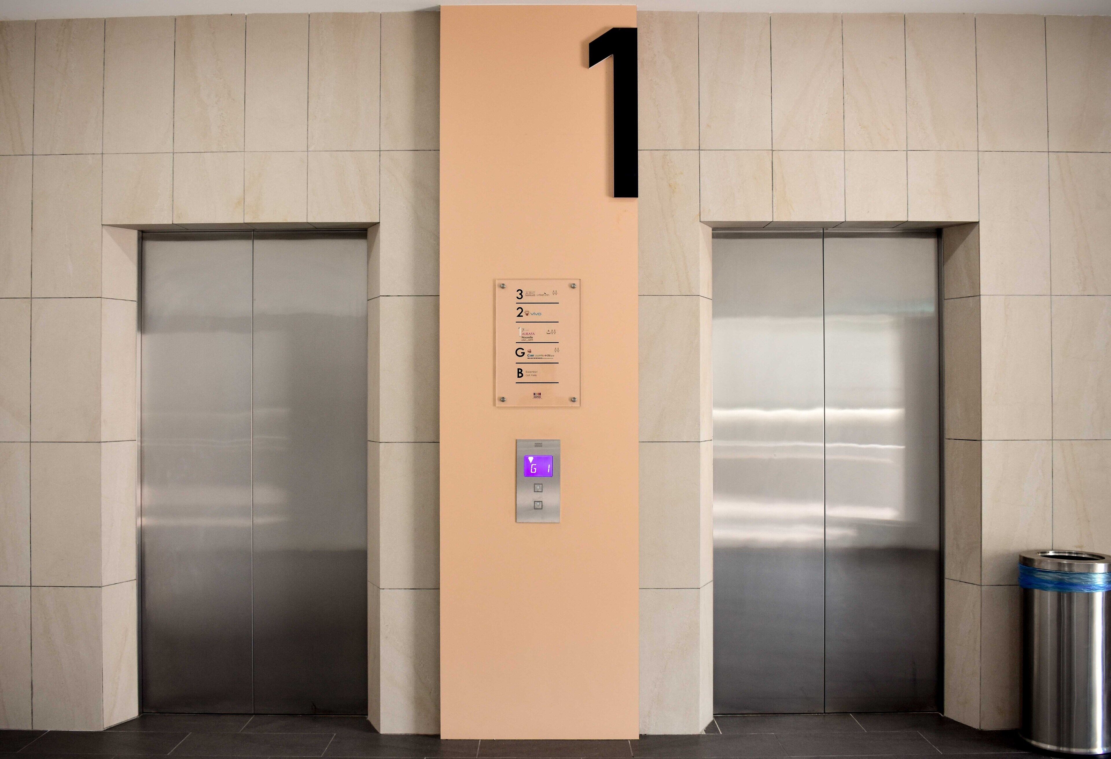A modern elevator with a digital display, a wall-mounted number 1 sign, and a floor indicator.