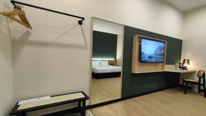 A hotel room with a bed, a desk with a chair, a bench, a mirror, and a television. - Urban Inn Alor Setar (Alor Setar)