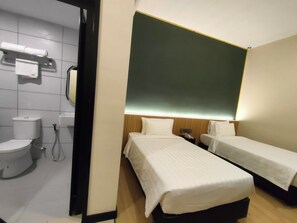 A hotel room with two single beds, a toilet, and a shower area.