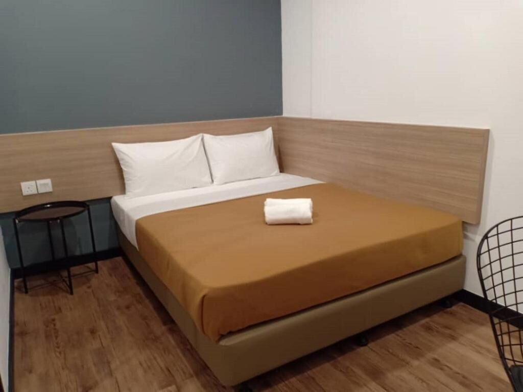 A hotel room with a bed, a small table, and a chair.