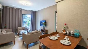 A modern hotel room with a dining area, a sofa set, a TV, and a balcony with curtains. - eStay Residence - Guangzhou Peace World Plaza (Guangzhou)