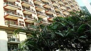 A high-rise building with multiple balconies, surrounded by lush green trees. - eStay Residence - Guangzhou Peace World Plaza (Guangzhou)