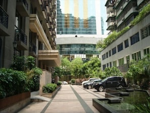 Residents enjoy a tranquil courtyard with a water feature and lush greenery, surrounded by balconies and large windows.