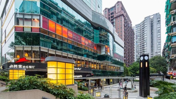 A modern hotel with a glass facade, multiple floors, and a prominent clock tower. - eStay Residence - Guangzhou Peace World Plaza (Guangzhou)