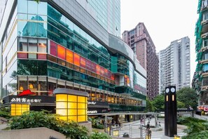 A modern hotel with a glass facade, multiple floors, and a prominent clock tower. - eStay Residence - Guangzhou Peace World Plaza (Guangzhou)
