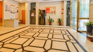 A spacious lobby with a geometric patterned floor, a reception desk, potted plants, and a modern ceiling design. - eStay Residence - Guangzhou Peace World Plaza (Guangzhou)