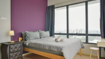 A bedroom with a bed, a nightstand, a lamp, a window with a view of buildings, and a small table.