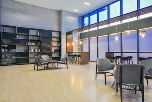 A modern library with bookshelves, seating areas, and large windows.