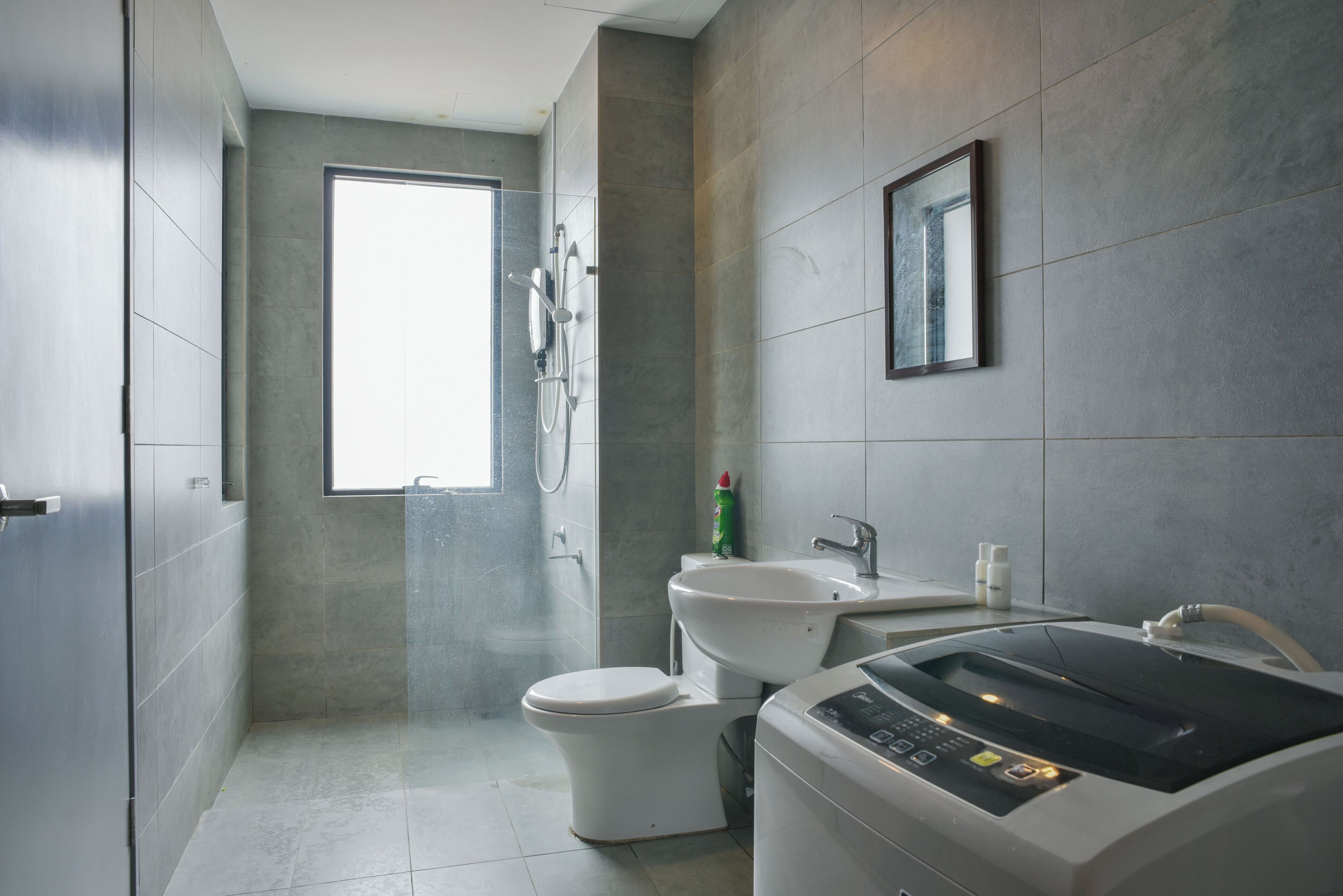 A modern bathroom with a shower, toilet, and a washing machine.