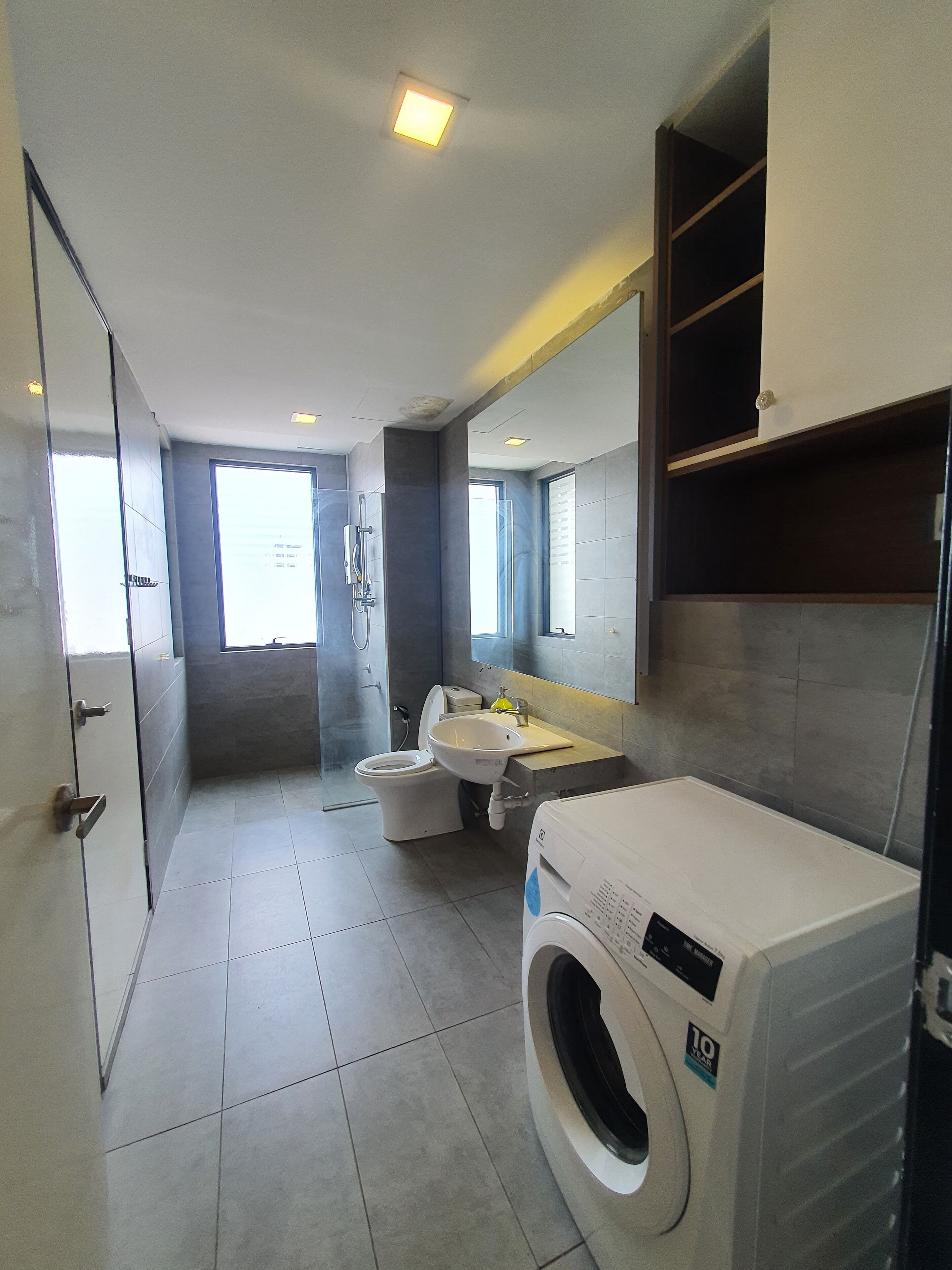 A modern bathroom with a built-in washer and dryer, a glass shower enclosure, and a vanity with a mirror.