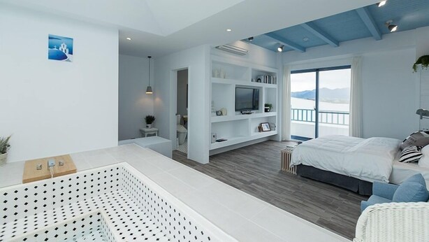 Quarto moderno com uma cama grande, televisão e varanda com vista.