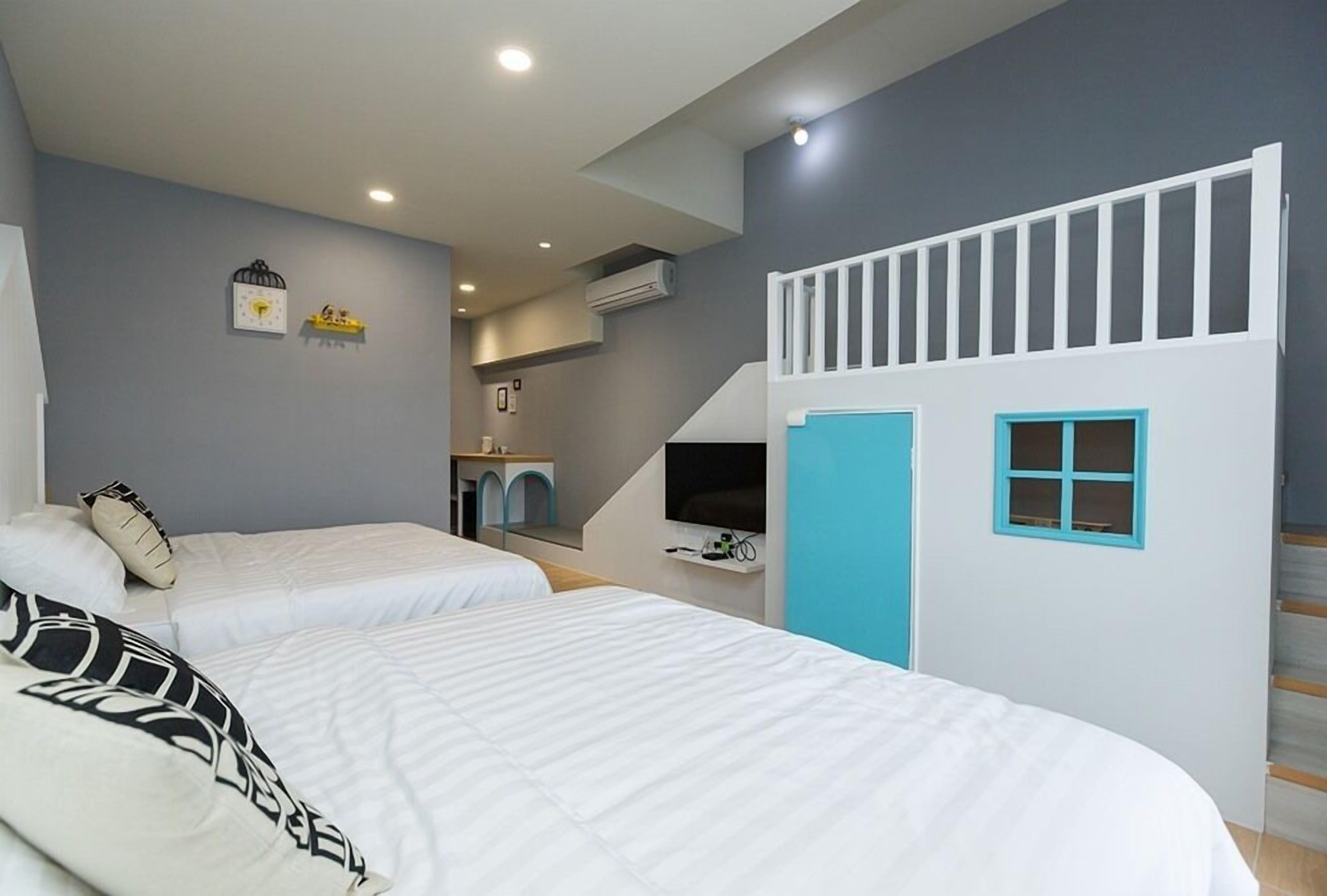 Quarto com duas camas, um rancho infantil e um lance de escadas.