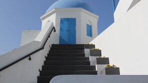 Um edifício branco com uma cúpula azul e uma porta azul, com um lance de escadas pretas.