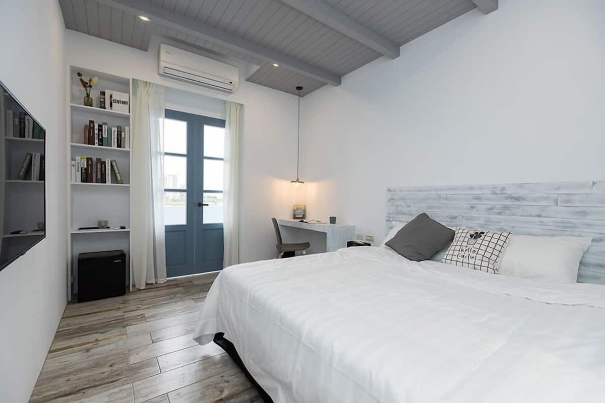 Une chambre à coucher comprenant un lit, un bureau, une chaise, une bibliothèque et un appareil de climatisation.