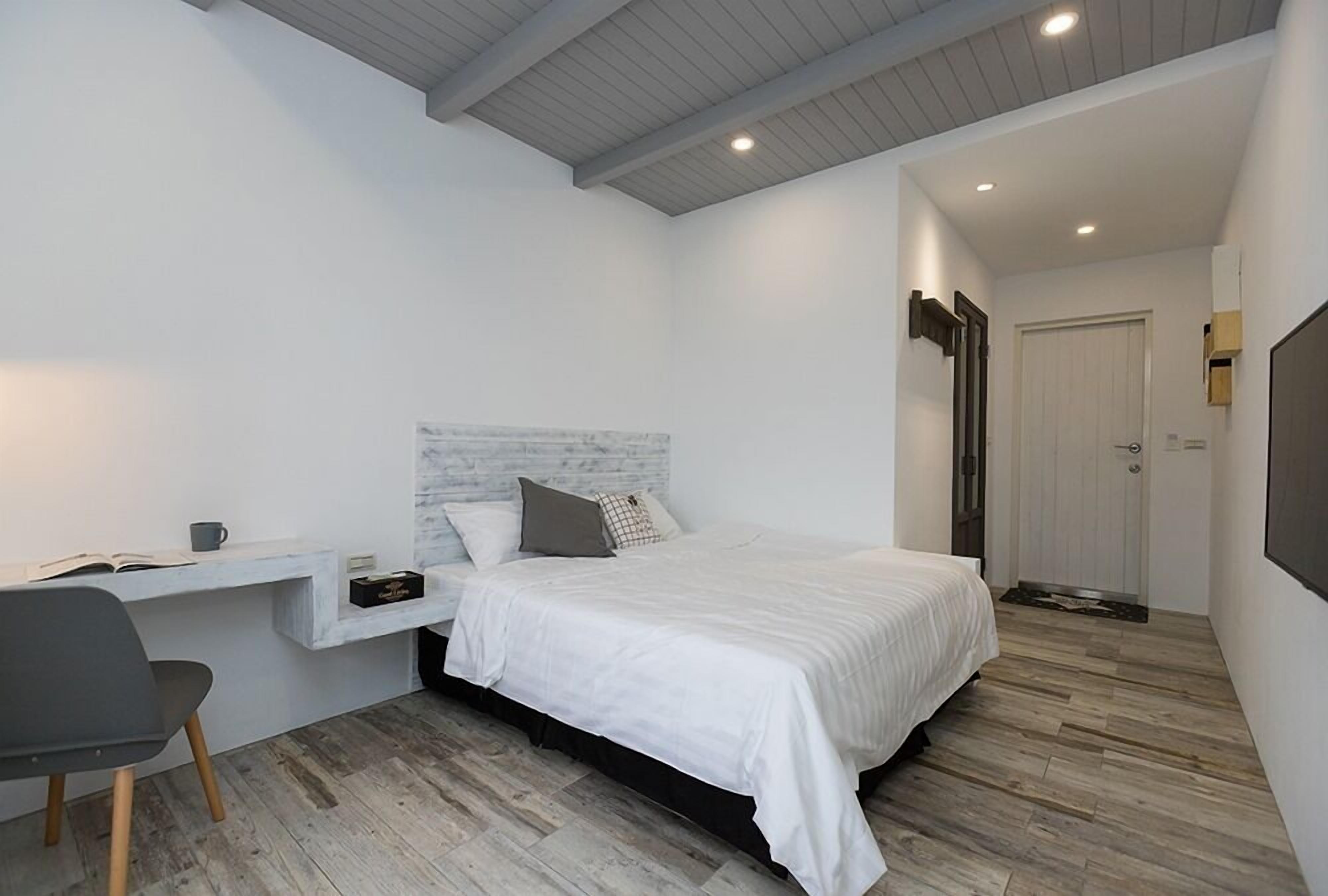 Un dormitorio con cama, escritorio y silla.