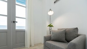 Uma sala de estar moderna com um sofá cinzento, um abajur e uma planta em vaso.