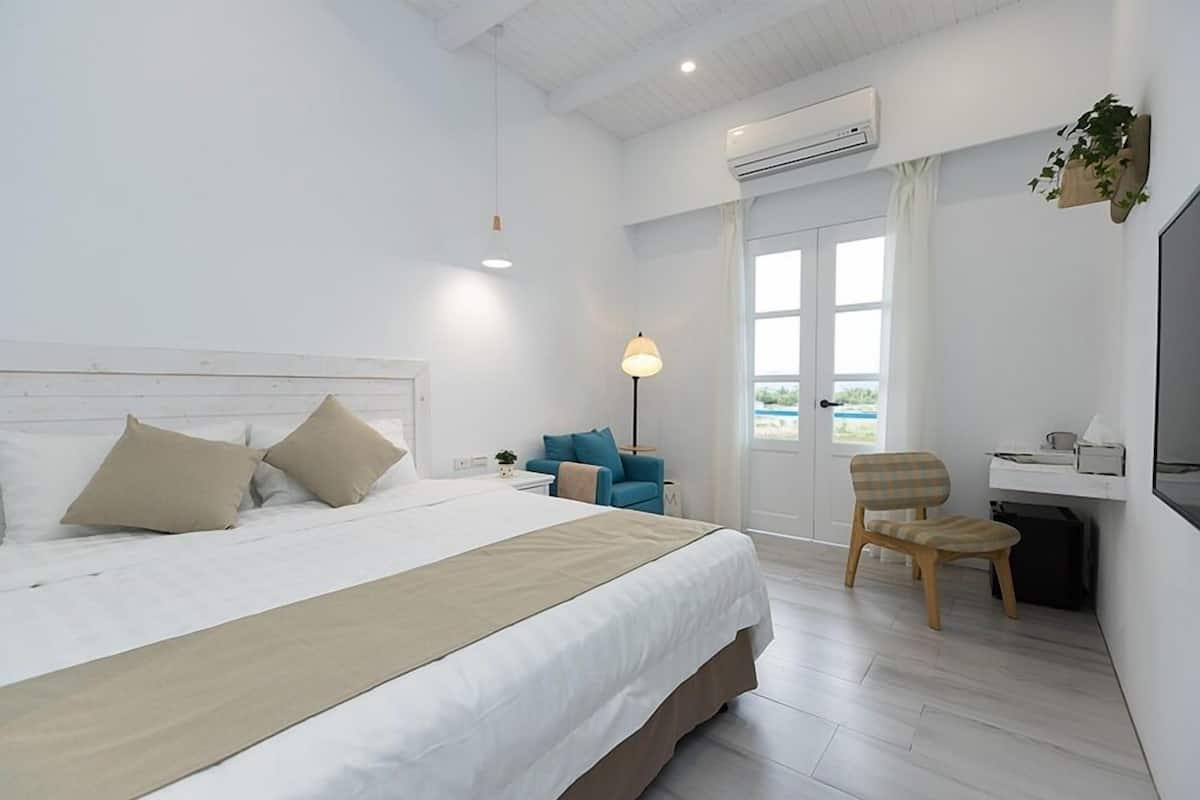 Une chambre d’hôtel moderne, dotée d’un grand lit, d’un bureau, d’une chaise et offrant une vue sur l’extérieur.