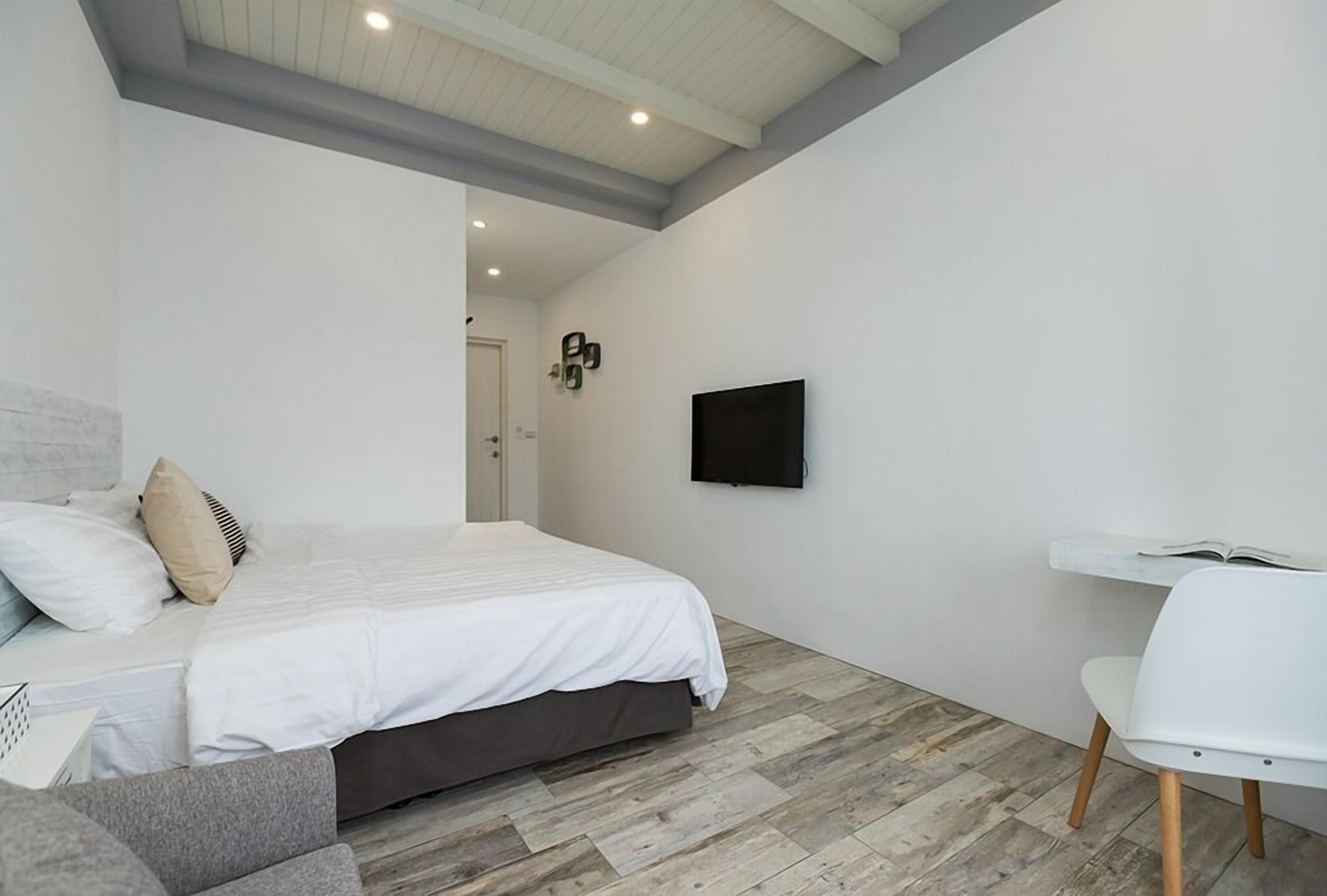 Un dormitorio con cama, escritorio y televisor en la pared.