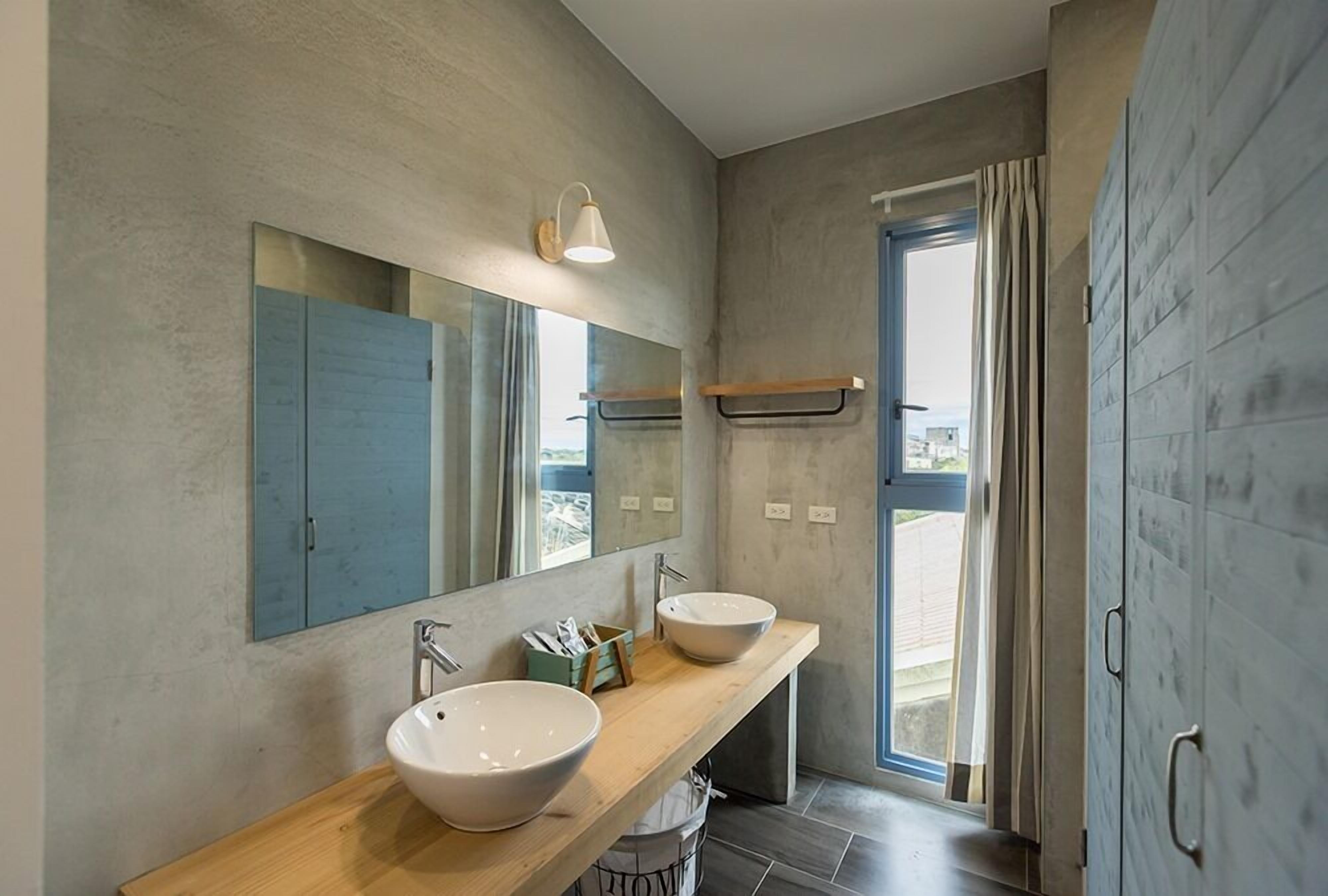 A modern bathroom with two sinks, a large mirror, and a shower area.