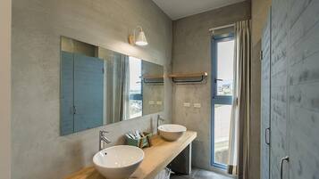 A modern bathroom with two sinks, a large mirror, and a shower area.
