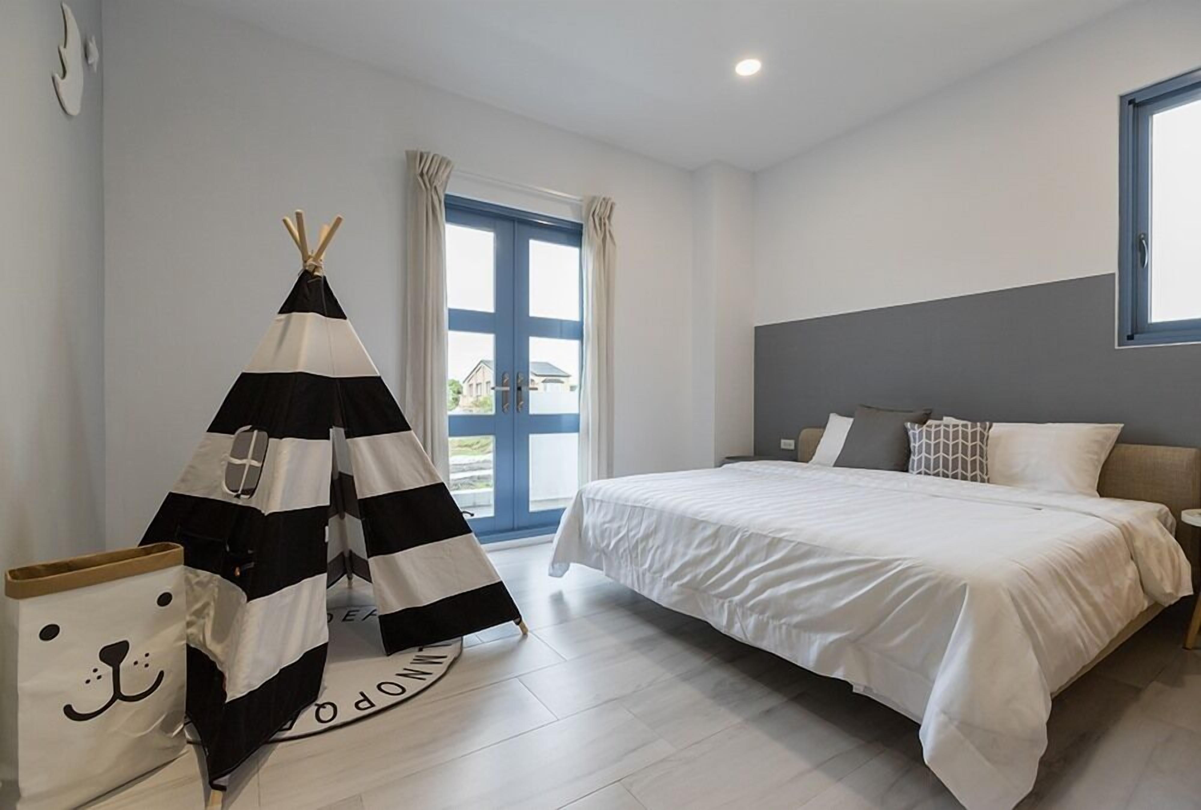 Une chambre à coucher avec un lit, des rideaux, une fenêtre et une structure en forme de tipi.