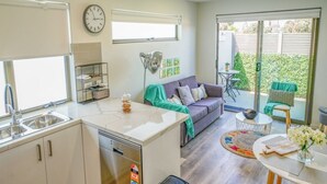 A modern kitchen with white cabinets, a built-in dishwasher, and a window above the sink. - U201 Brunswick Living Top flor Balcony Close to APT n CBD FreeWifi Tram Doorstep (Brunswick West)