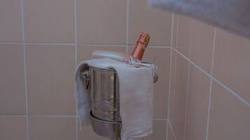 A towel dispenser with a bottle of champagne in a tiled bathroom.