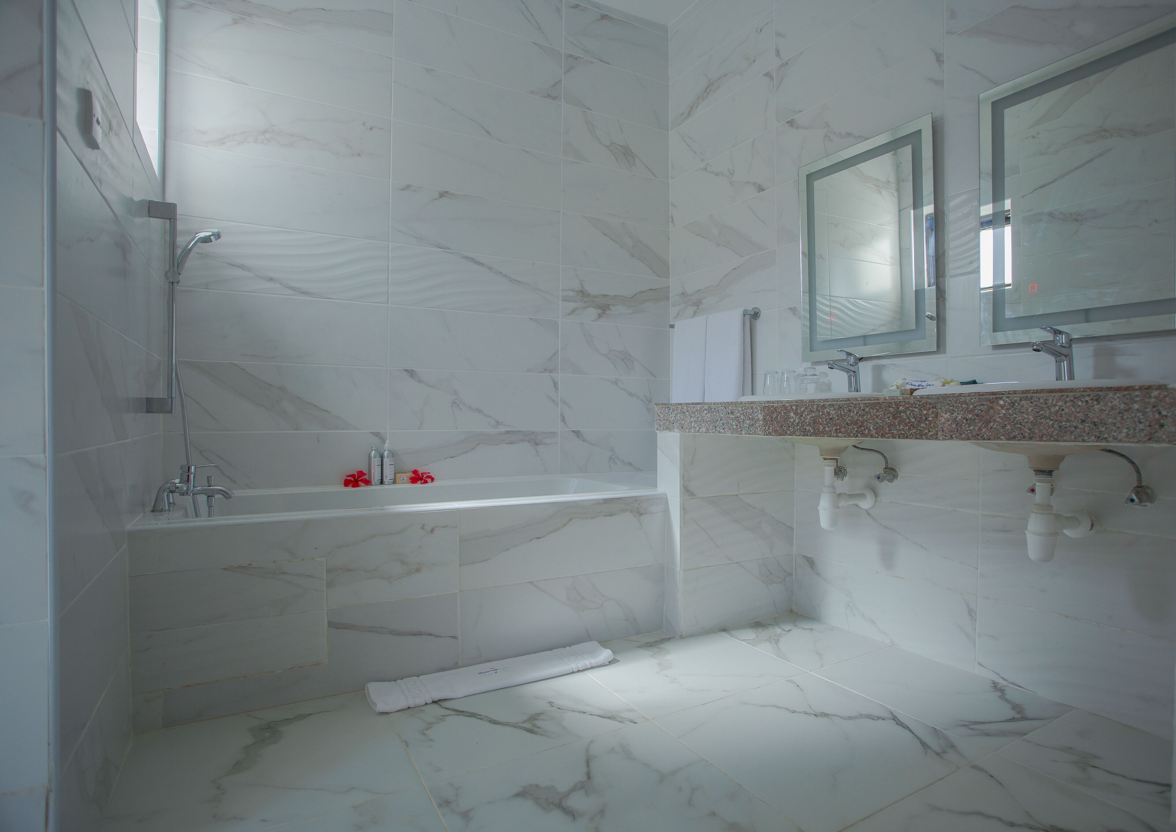 A bathroom with a bathtub, a shower, and a sink with a mirror above it.