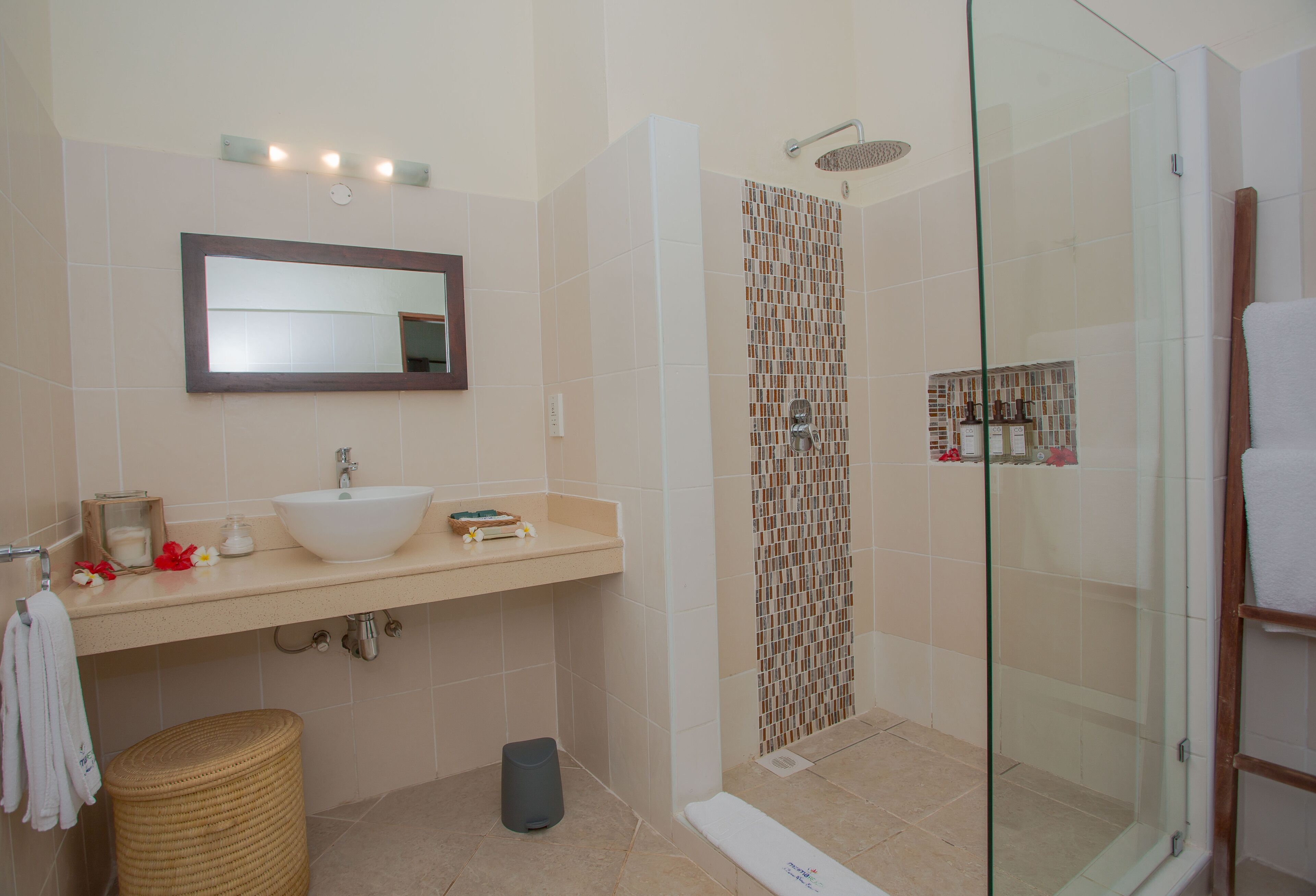 Un baño moderno con lavamanos, espejo y ducha.