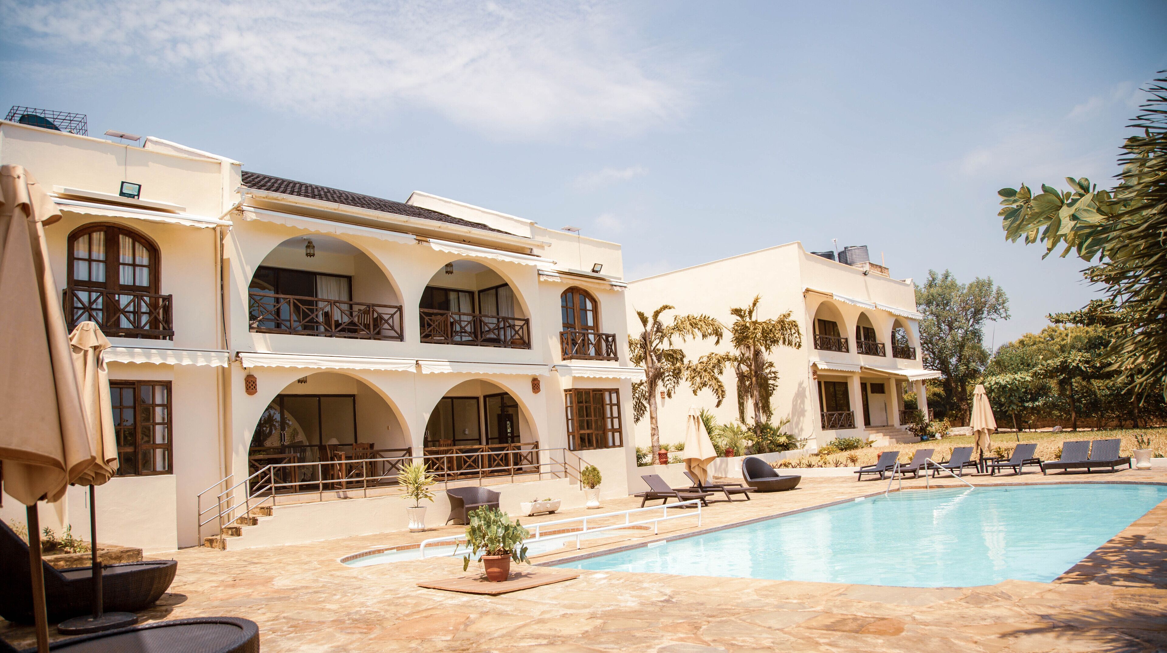A hotel with a pool, outdoor seating, and multiple balconies.