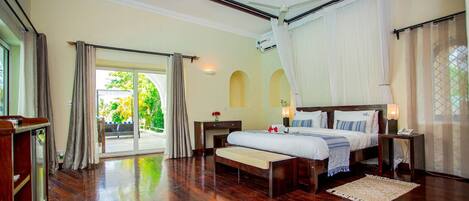A spacious bedroom with a large bed, a bedside table, a nightstand, a ceiling fan, and a view of the outdoors through a glass door.