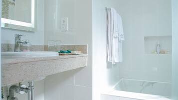 Un baño moderno con ducha envuelta en vidrio, un lavabo con encimera de granito y un espejo sobre el lavabo.