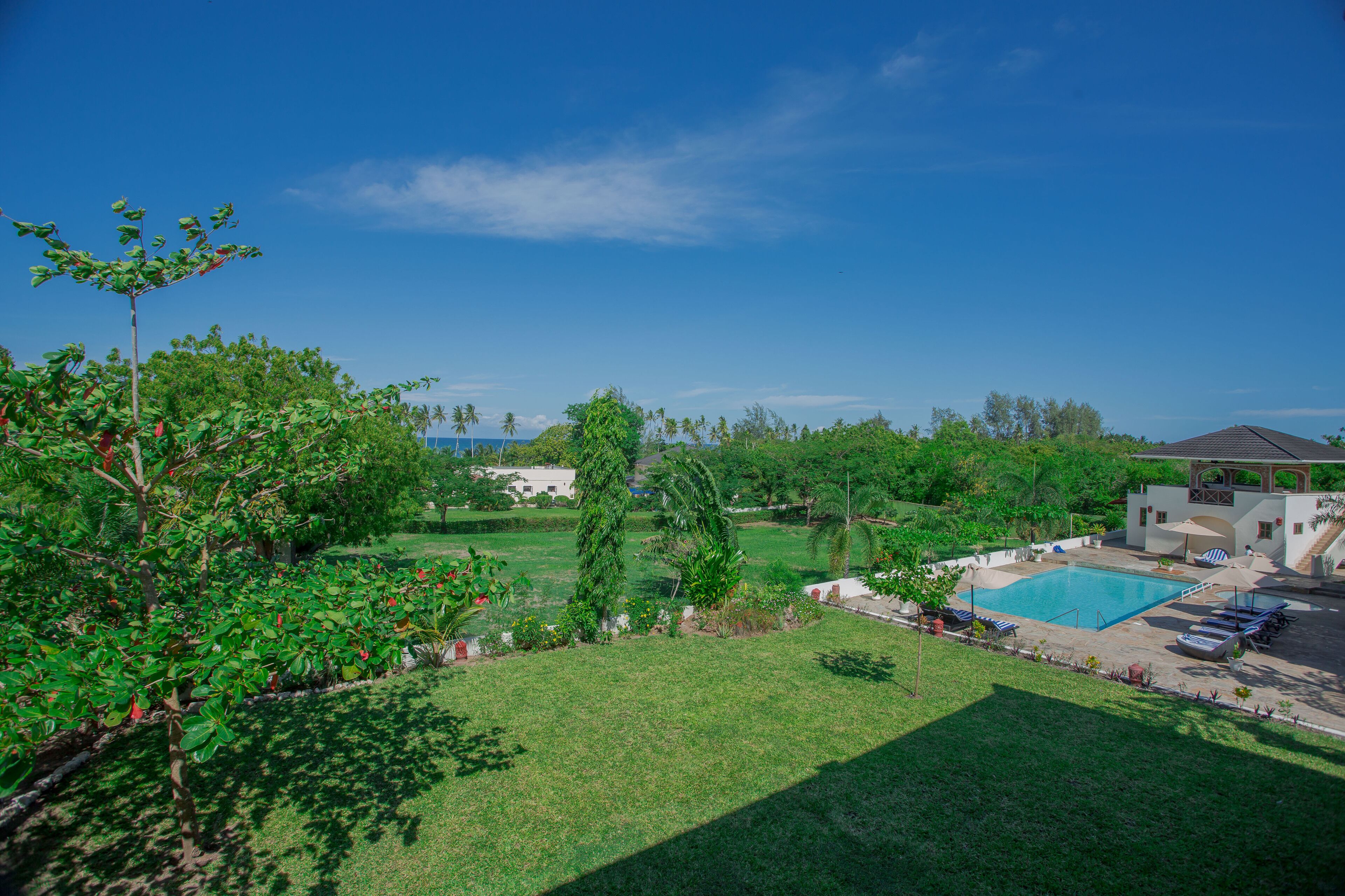 A pool area with a clear view of the surrounding landscape, including a grassy lawn and trees.