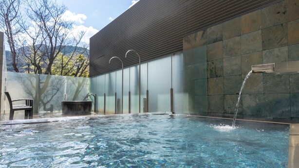 An outdoor swimming pool with clear water, a bench, and a water feature. - Yamamura Annex (Nagato)
