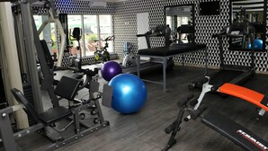 Un gimnasio con equipo de ejercicio, una cinta de correr y pelotas de gimnasia.