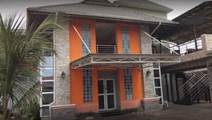 Un edificio de dos plantas con fachada de piedra, detalles en naranja y un área de entrada cubierta.