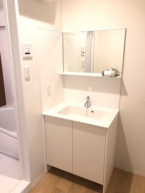 Une salle de bain avec un lavabo blanc, un miroir et un distributeur de serviettes.
