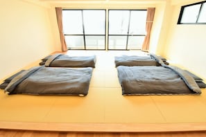 Une chambre avec deux lits, une grande fenêtre et un plancher en bois.