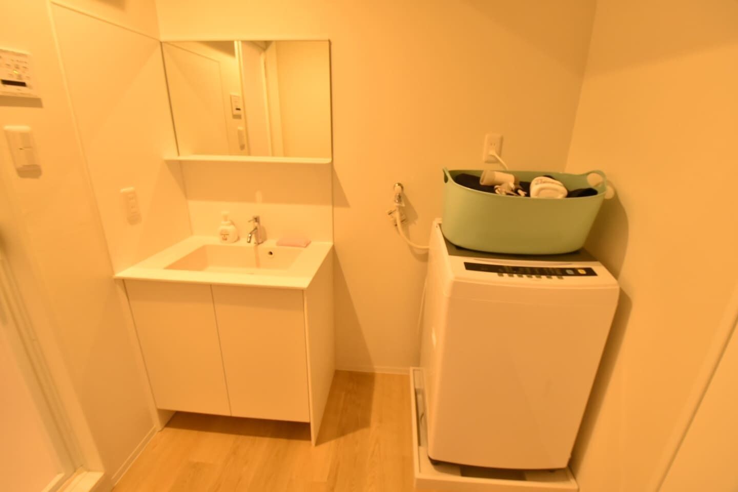 Un baño pequeño con lavamanos, espejo y lavadora compacta.