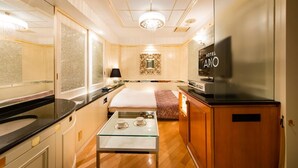 A hotel room with a bed, a glass table with two cups, a TV, and a minibar. - HOTEL APiO - Adults Only (Tokyo)