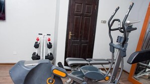 A gym with exercise equipment, including a treadmill, elliptical, and dumbbells. - Newton Hotel Festac (Lagos)
