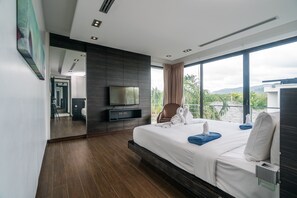 A modern hotel room with a large bed, a flat-screen TV, a seating area with a chair, and a balcony with a view of greenery. - Diamond VIP villas by Lofty (Choeng Thale)