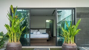 Ein modernes Hotelzimmer mit einem Bett, zwei Blumentöpfen und einer Fußmatte.