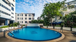 A swimming pool with a tiled deck, surrounded by buildings and greenery. - Patong Tower by Lofty (Patong)