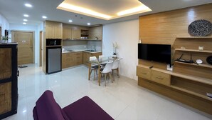 A modern kitchen with a dining area, a TV, and a flat-screen TV on a wooden wall. - Patong Tower by Lofty (Patong)
