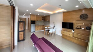 A modern kitchen with wooden cabinets, a dining area with a glass table, and a bench. - Patong Tower by Lofty (Patong)