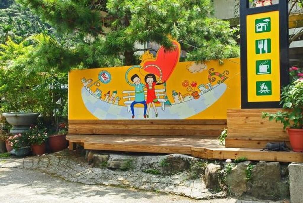 A colorful mural with a heart-shaped design, a bench, and a sign with icons indicating amenities.